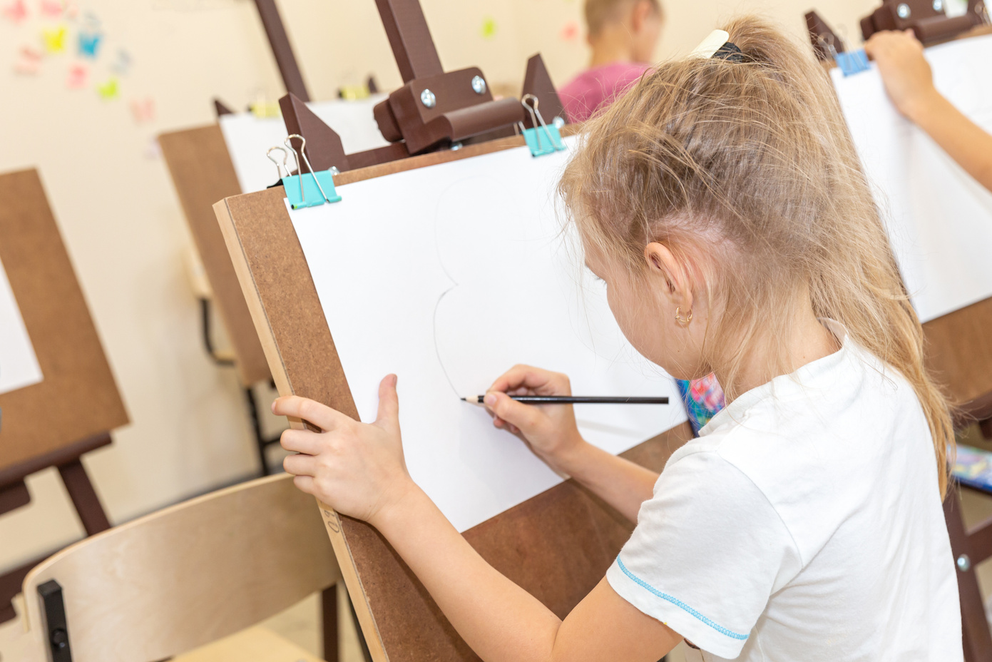 Kid Drawing Image on Easel in Classroom